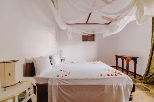 a bedroom with a bed with red rose petals on it at Exploreans Malaika Villas and Beach Club in Malindi