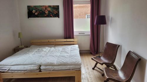 a bedroom with a bed and two chairs and a window at Gemütliches Apartment im Grünen mit Kamin und Klöntür in Altenmedingen