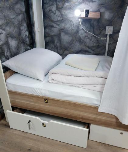a bed in a room with white sheets and pillows at King Hostel in Old City in Baku