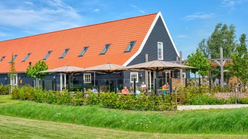 a building with an orange roof and a restaurant at Dutchen Erfgoedpark De Hoop Appartementen in Uitgeest