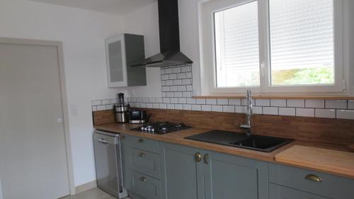 une cuisine avec un évier, une cuisinière et une fenêtre dans l'établissement Au petit moulin, à Issigeac