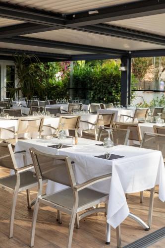 a row of white tables and chairs in a restaurant at Bella Vista Hôtel, Suites & Maisons in Porticcio