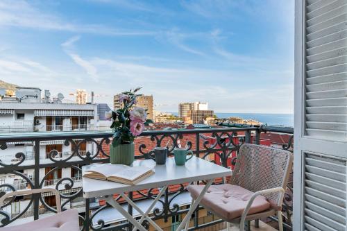- un balcon avec une table, un livre et des fleurs dans l'établissement Monaco Seaview Border - 1bdr flat - 2beds - 4 guests, à Beausoleil