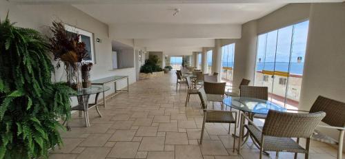 a dining room with tables and chairs and the ocean at COBAR0108 - Edifício Oceania in Salvador