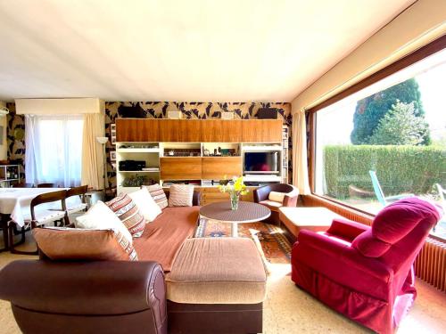 Elle comprend un salon doté d'un mobilier rouge et d'une grande fenêtre. dans l'établissement Happy Days - 5 chambres- jardín Parenthèse rétro en famille, à Friaucourt