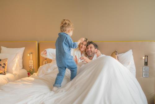 a little girl jumping on top of a bed at Pullman Toulouse in Blagnac