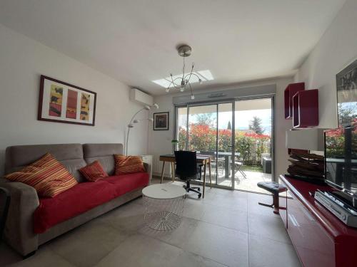 un salon avec un canapé rouge et une table dans l'établissement Charmant 2P climatisé avec terrasse et jardin, centre-ville Le Lavandou - FR-1-308-187, au Lavandou