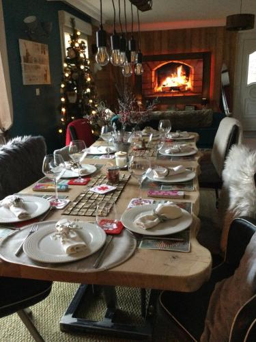a table with plates and glasses and a christmas tree at LA MAISON D'ULYSSE spa et détente in Anould