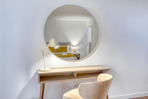 a mirror on a wall with a desk and a chair at Mouraria Studios in Funchal