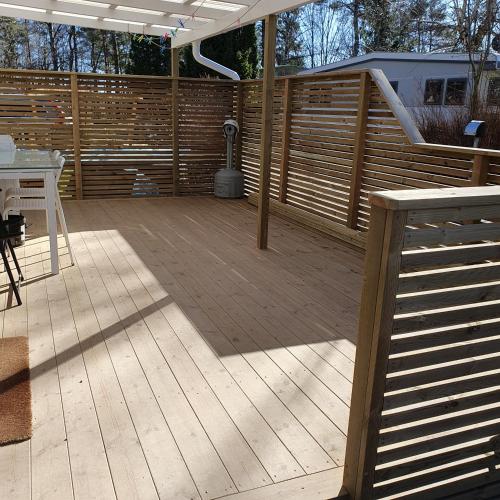 a patio with a fence and a table on a deck at Lilla stugan nära Kungsbacka in Fjärås