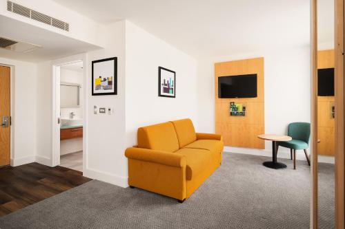 a living room with a yellow chair and a table at Holiday Inn Birmingham City by IHG in Birmingham