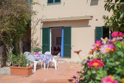 a patio with a table and chairs and flowers at Capo Bianco Terrace - Helloelba in Portoferraio