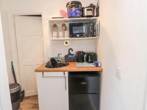 a kitchen with a counter with a microwave and a computer at Tanyfron Holiday Studio in Holyhead