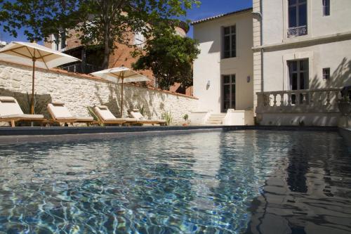 une piscine avec chaises et parasols à côté d'un bâtiment dans l'établissement Villa Meridia, à Nîmes