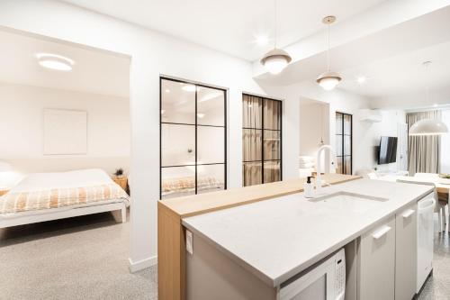 a white kitchen with a sink and a bedroom at Loft Deluxe & Fun - Downtown Quebec in Quebec City