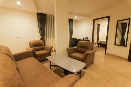 a living room with a couch and two chairs and a table at Hotel Vedanta Pride Hubballi in Hubli