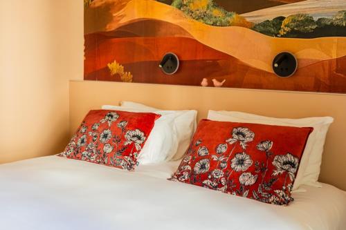a bedroom with a bed with two pillows and a painting at Garlande Hôtel Avignon Centre in Avignon