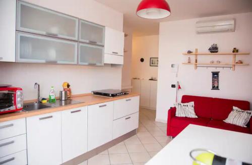 eine Küche mit weißen Schränken und einem roten Sofa in der Unterkunft Casa Anna in Marina di Montenero