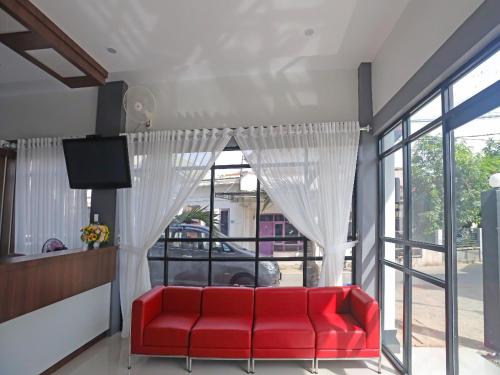 a red couch in a room with a window at Capital O 92096 Kuala Ulee Lheue Residence Syariah in Banda Aceh