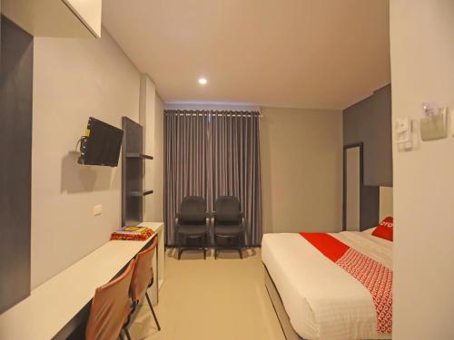 a hotel room with a bed and two chairs at Capital O 92096 Kuala Ulee Lheue Residence Syariah in Banda Aceh