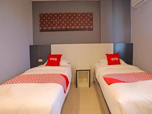 two beds in a room with red pillows on them at Capital O 92096 Kuala Ulee Lheue Residence Syariah in Banda Aceh