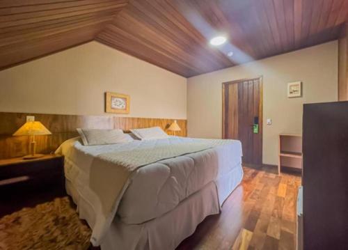 a bedroom with a large bed with a wooden ceiling at Pousada Victoria Villa By Nacional Inn - A 800 metros da Vila Capivari in Campos do Jordão