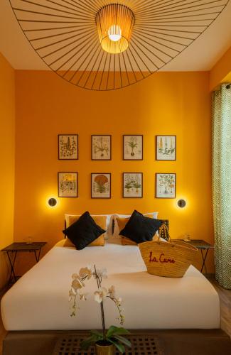 a bedroom with a large bed with an orange wall at Garlande Hôtel Avignon Centre in Avignon