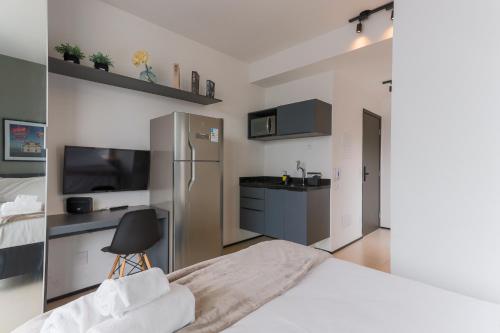 a bedroom with a bed and a kitchen with a refrigerator at 360 VN Turiassú by Housi in Sao Paulo