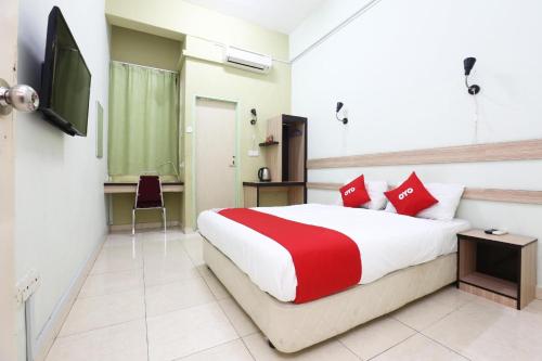 a bedroom with a red and white bed and a television at Hotel O Green Mango @ Sri Cemerlang in Kota Bharu
