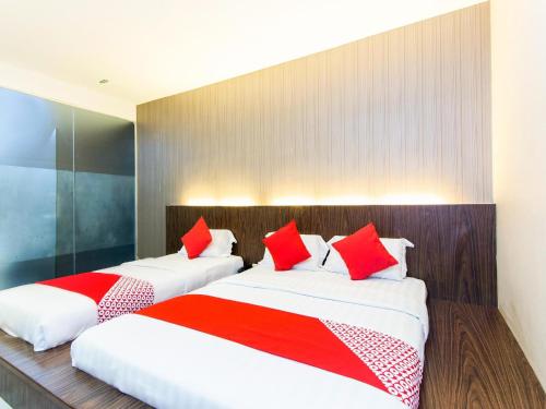 two beds in a hotel room with red pillows at Hotel O 340 Comfort Hotel in Kampong Batu Belah