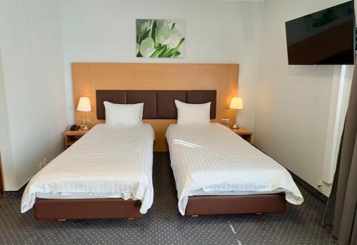 two beds in a small room with two lamps at Poleczki Residence Apartments in Warsaw