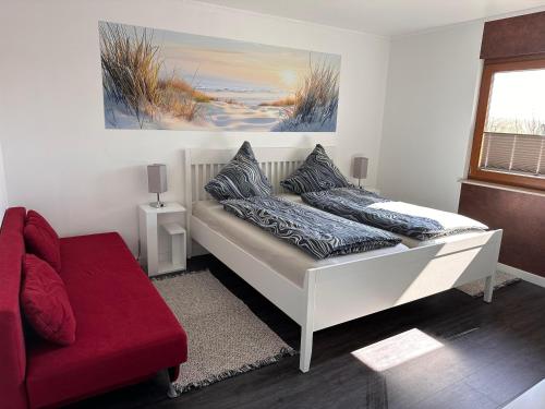 a bedroom with a bed and a red couch at URLAUB mit HUND -Ferienwohnung "AhriBella"- in Glowe
