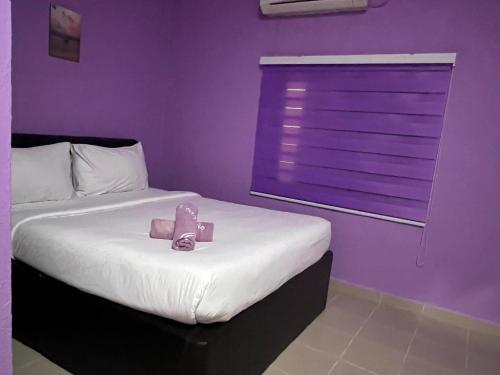 a bedroom with a bed with a purple wall at Hotel O Brick Cottage Homes in Kuah