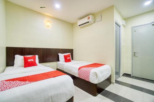 a room with two beds with red and white sheets at OYO 89960 Manjung Inn Hotel in Seri Manjung