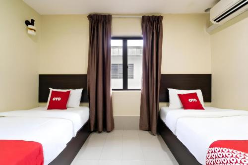 two beds in a room with red pillows at OYO 89960 Manjung Inn Hotel in Seri Manjung