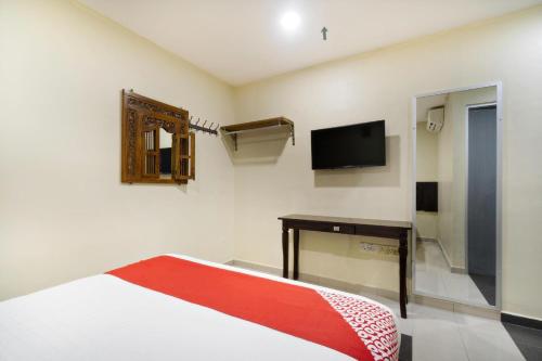 a bedroom with a bed and a tv on the wall at OYO 89960 Manjung Inn Hotel in Seri Manjung