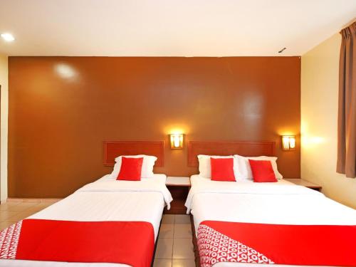 two beds in a room with red and white pillows at Super OYO 447 Comfort Hotel Meru in Klang