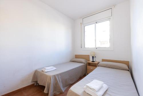 two beds in a white room with a window at Rentalmar Brisas in Miami Platja