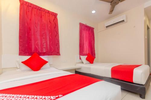 two beds in a room with red curtains at Skudai Hotel in Skudai