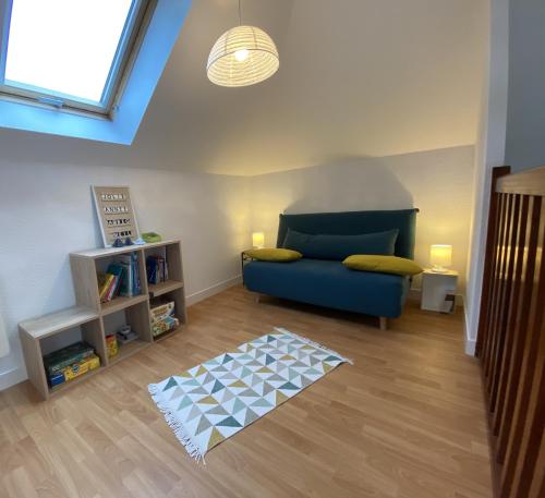 a living room with a blue couch and a book shelf at Fouesnant Beg Meil, duplex au coeur du village, à 450 m de la plage in Beg-Meil