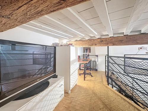 un salon avec une grande télévision et une table dans l'établissement Le studio Mezz, charmant studio avec mezzanine, à Montpellier