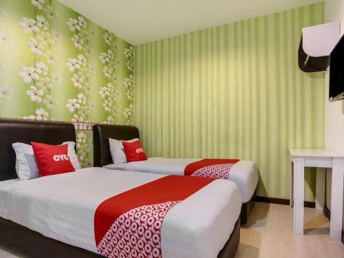 two beds in a room with green and red at OYO 89583 Grove Hotel in Kajang
