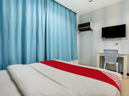 a bedroom with a bed with blue curtains and a desk at OYO 89583 Grove Hotel in Kajang