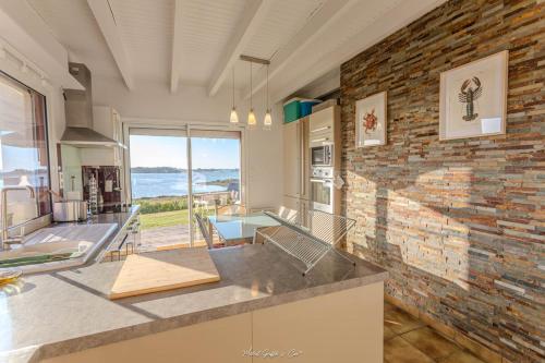 Il dispose d'une cuisine et d'un salon avec un mur en briques. dans l'établissement Maison pour 7 - Superbe vue mer depuis le jardin, à Penvénan