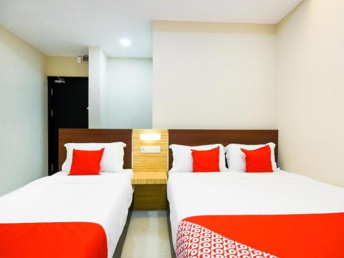 two beds in a hotel room with red pillows at Hotel O La Mirina Boutique Inn in Miri