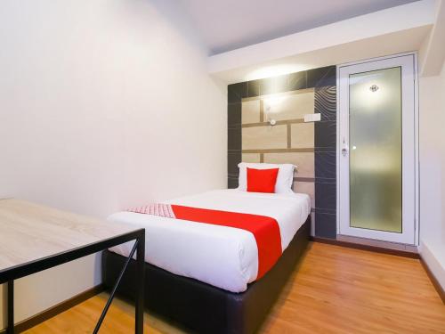 a bedroom with a white bed with a red pillow at Hotel O La Mirina Boutique Inn in Miri