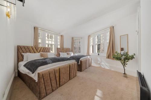 two beds in a room with white walls and windows at Prime Soho 3-Bedroom Apartment Steps from Piccadilly and Chinatown! No Lift 3GH in London