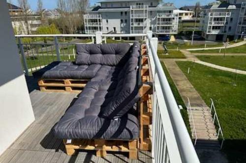 2 chaises assises sur une terrasse sur un balcon dans l'établissement Superbe appartement neuf avec un grand balcon - Cabourg - Welkeys, à Cabourg