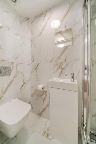 a white bathroom with a toilet and a sink at Prime Soho 3-Bedroom Apartment Steps from Piccadilly and Chinatown! No Lift 3GH in London