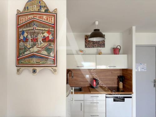 une cuisine avec un tableau accroché au mur dans l'établissement 6 PERS, 2 CHAMBRES, DERNIER ETAGE EN FRONT DE MER, à Sète